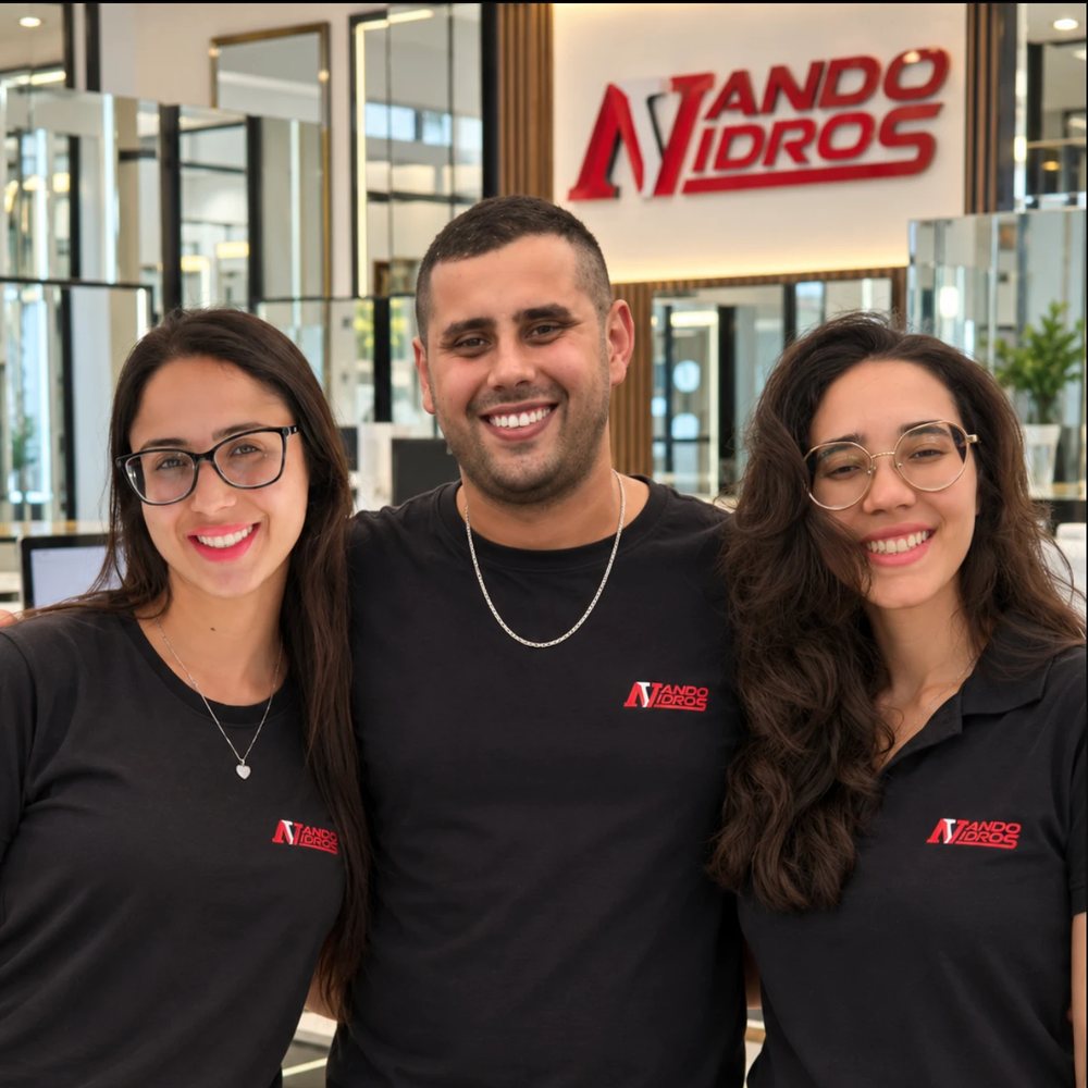 Fernando, Bruna e Camila sorrindo na loja da Nando Vidros, com a logo ao fundo